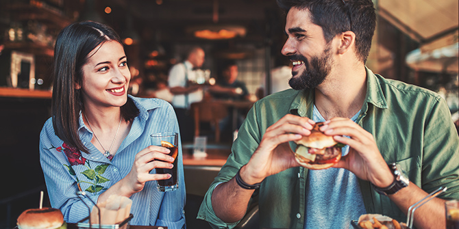 Casual couple eating burgers together.